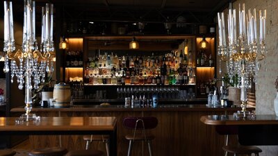 Bar lined with many bottles of alcohol and standing candlestick holders