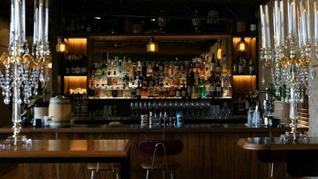 Bar lined with many bottles of alcohol and standing candlestick holders