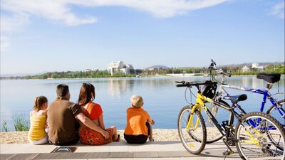Family sitting on waters edge in Canberra with bikes from Cycle Canberra