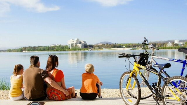 Family sitting on waters edge in Canberra with bikes from Cycle Canberra