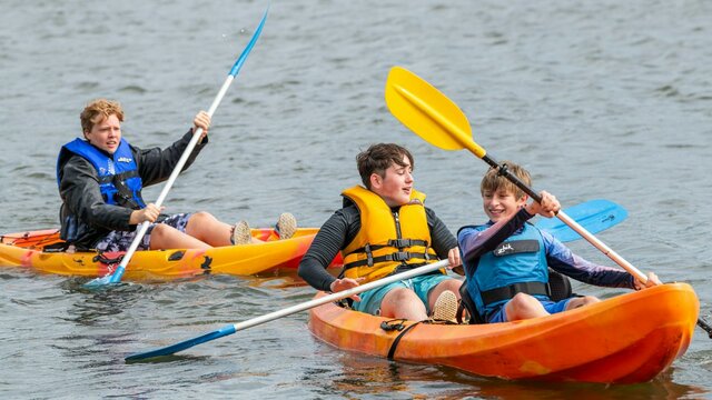 3 Male Youth on Double and Single Kayak in water