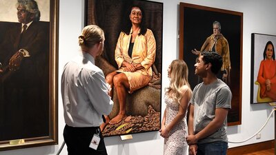 People facing portraits on a wall