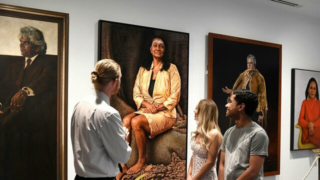 People facing portraits on a wall