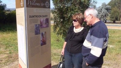 Man and Woman outdoors looking at tall sign