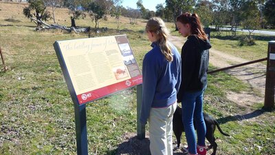 two teenage girls with dog looking at sign