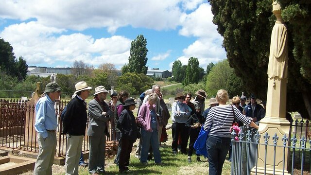 Interesting stories abound at Riverside Cemetery Group of people standing in old cemetery with large cypress and stone tombstones