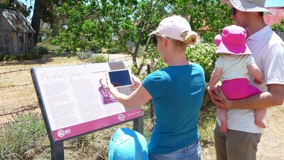 Two adults and two children looking at information panel outdoors