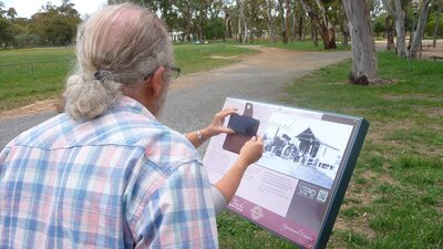 Back of man looking at information board in park setting