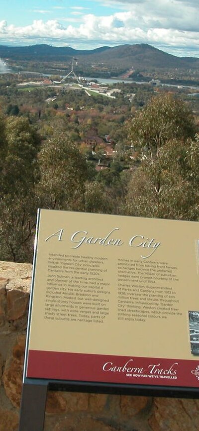 Information panel against stone wall with view of trees and hills