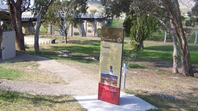 Tall information panel with park and bridge in background