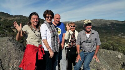 Four seniors and tour guide at Charlotte pass lookout with Mount Kosciuszko behind