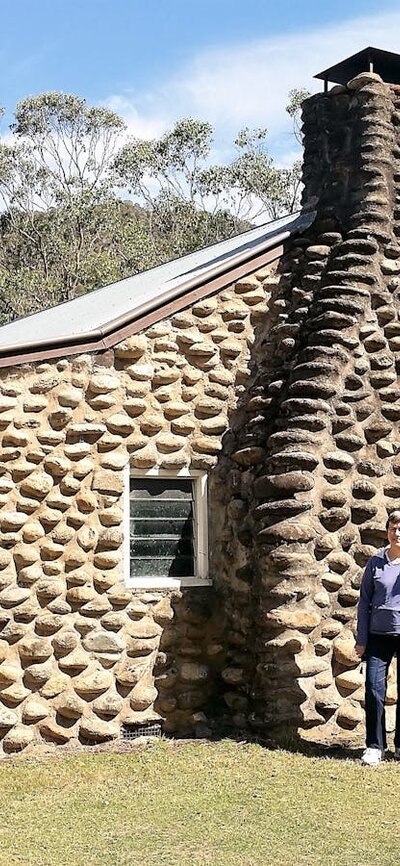 two women standing in front of hut made from river rock