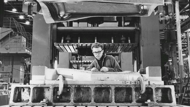 Black and white photograph of of a mechanic working on a Holden car