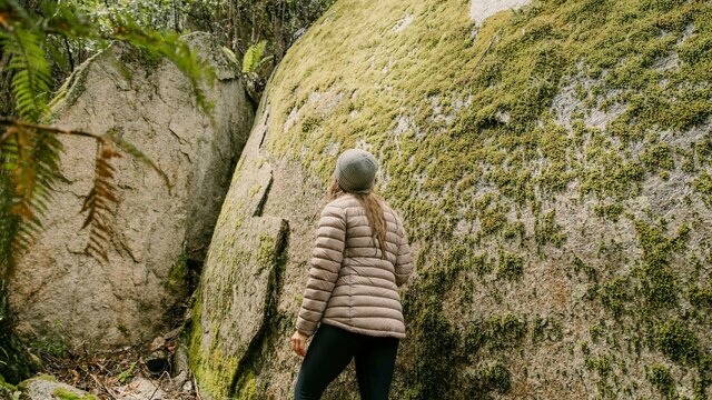 We Are Explorers for Visit Canberra Women hiking next to huge moss covered granite boulder