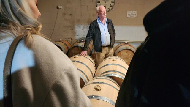 A man standing in front of a group of wooden barrels.