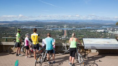 5 cyclists stand with their bikes behind the Marion Mahony Griffin View handrail.