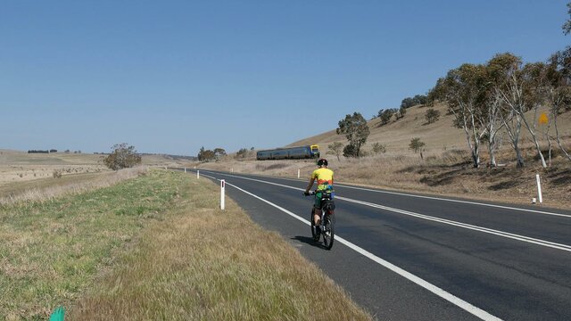 One of our cyclists on the road to Tarago with the Canberra to Sydney XPT heading towards Sydney. XPT train passing cyclist