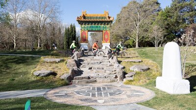 Three cyclists ride below the  traditional Chinese gate
