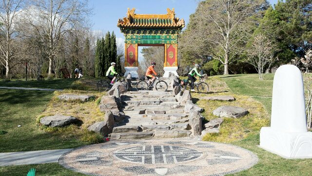 The Beijing Gardens next to Lake Burley Griffin Three cyclists ride below the traditional Chinese gate