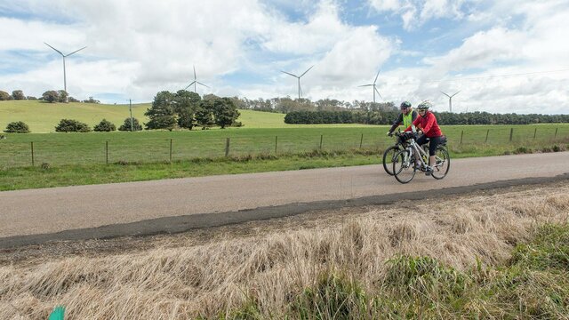 Two cyclists passing 5 wind turbines. Two cyclists passing 5 wind turbines.