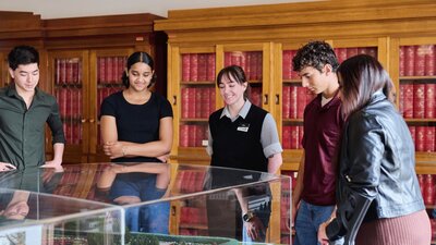 A group of people view a miniature version of Old Parliament House beneath a glass display cabinet