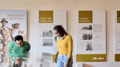 Two people observe a miniature version of Old Parliament House beneath a glass display case