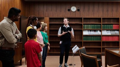 A MoAD Museum Experience Officer speaks to a group of people gathered in the Prime Minister's office