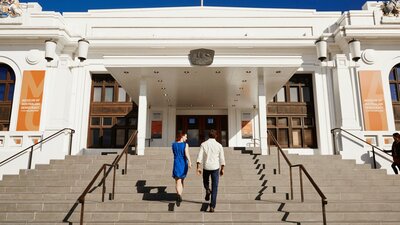 Two people walk up the steps of Old Parliament House