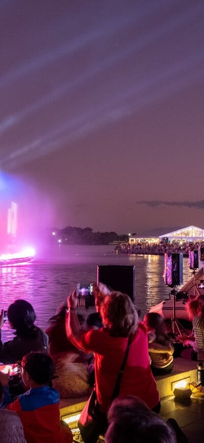 People gather aroudn a light display on Lake Burley Griffin