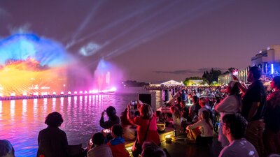 People gather aroudn a light display on Lake Burley Griffin