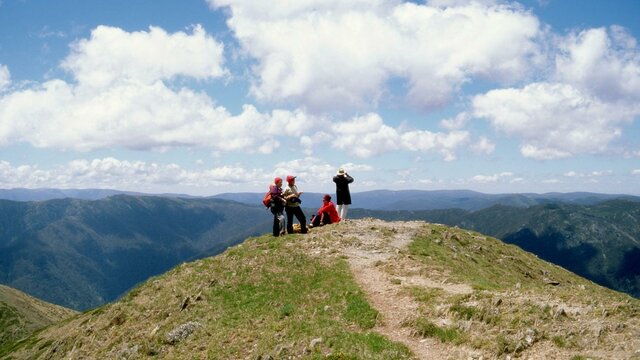Victorian Alps Four hikers on a hilltop path overlooking the mountains and valleys below in the Victorian Alps