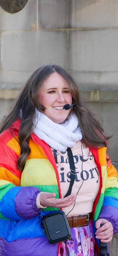 Tour guide Millie wearing a rainbow puffer jacket and headset
