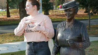 Tour guide Eliza standing next to statue of Dorothy Tangney