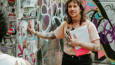 Tour guide Zev is touching wall covered in street art