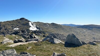 Large boulders in the mountains with some snow on a peak behind it.