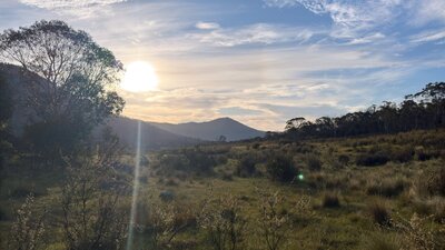 A mountain with the sun setting behind it.