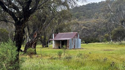 A metal hut in the middle of a grassy open plain.