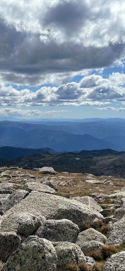 Views of the mountains with some rock in the foreground and heavy clouds above.