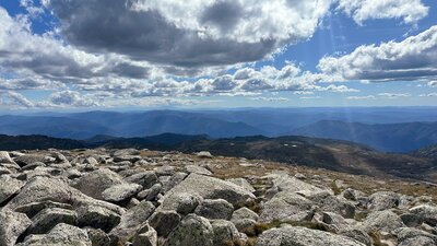 Views of the mountains with some rock in the foreground and heavy clouds above.