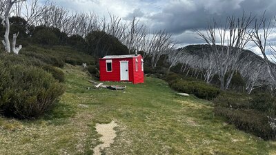 A red hut in the centre of the landscape with a mountain to the right.