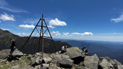 Three hikers at the top of a mountain looking at the view.