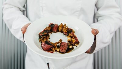 Chef holding a plate containing a dish made with truffle