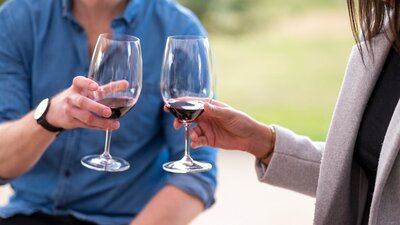 A couple are about to cheers red wine glasses on a wine tasting in Canberra