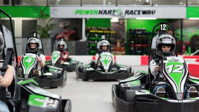 Five kart racers in protective helmets on a track