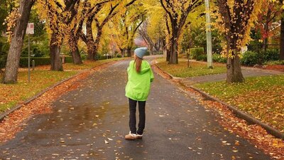 © @jujubdendey Girl in a bright green hoodie and grey hat standing in an autumnal neighbourhood street | © @jujubdendey