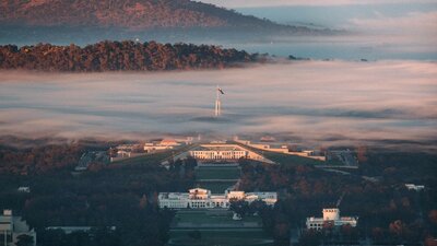 © @bentellier Purple and blue image of sunrise fog across Canberra, covering Australian Parliament House | © @bentellier