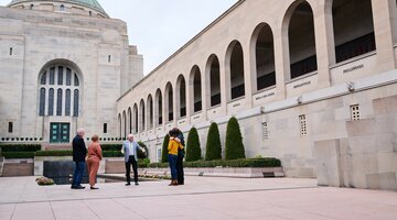 A group is with a tour guide in a courtyard section of the Australian War Memorial.