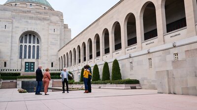 A group is with a tour guide in a courtyard section of the Australian War Memorial.