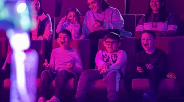 © Martin Ollman Kids around 7 years old sitting in purple light of a theatre in a live science show at Questacon | © Martin Ollman