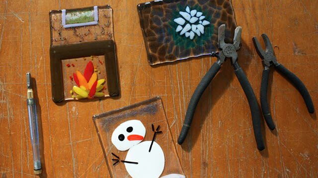 Canberra Glassworks school holiday program Tiles made from glass on a table with art making equipment and tools